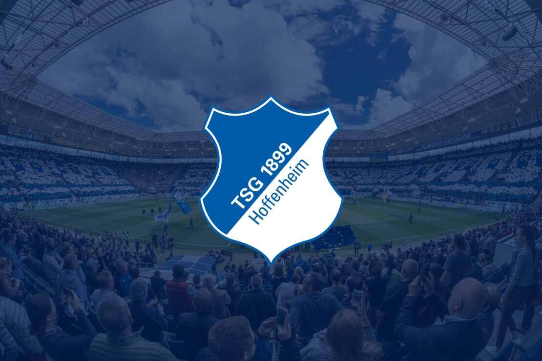 Logo der TSG Hoffenheim vor einem Stadion mit vielen Fans