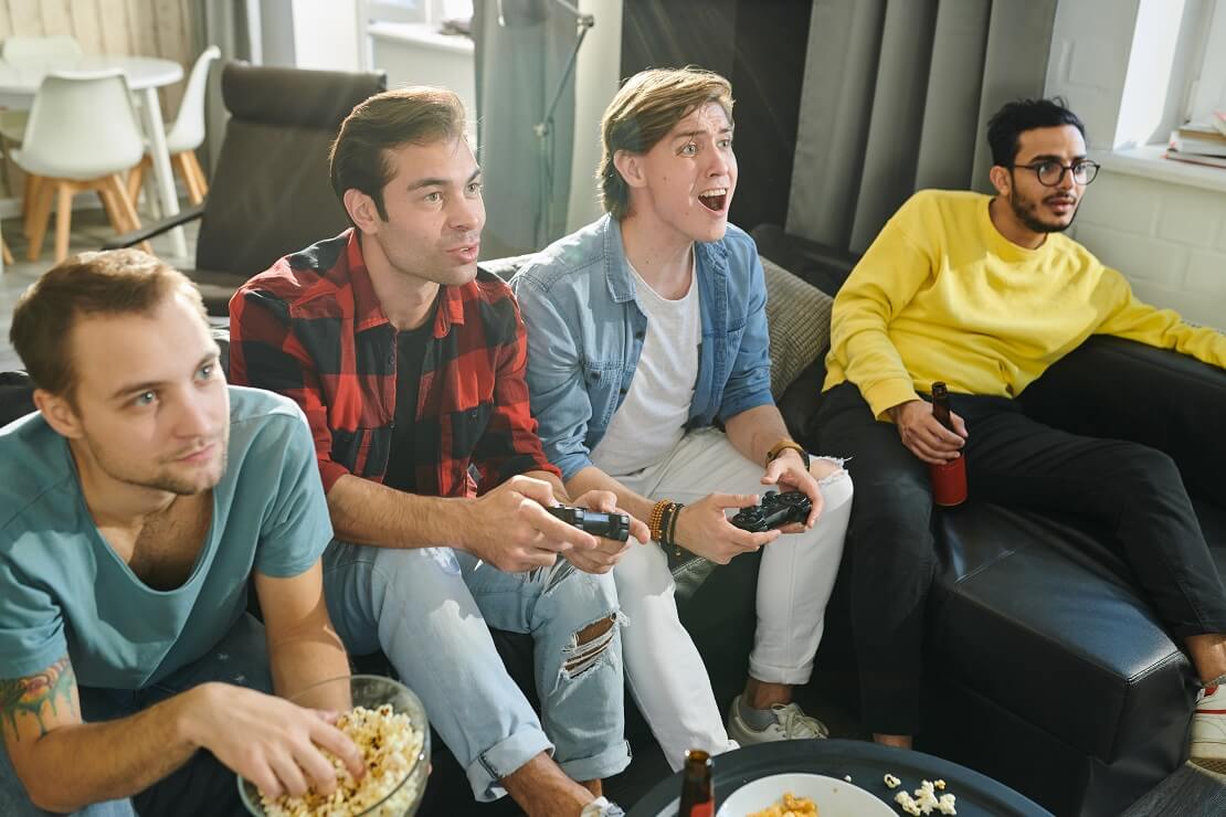 Männer sitzen auf der Couch und spielen Playstation