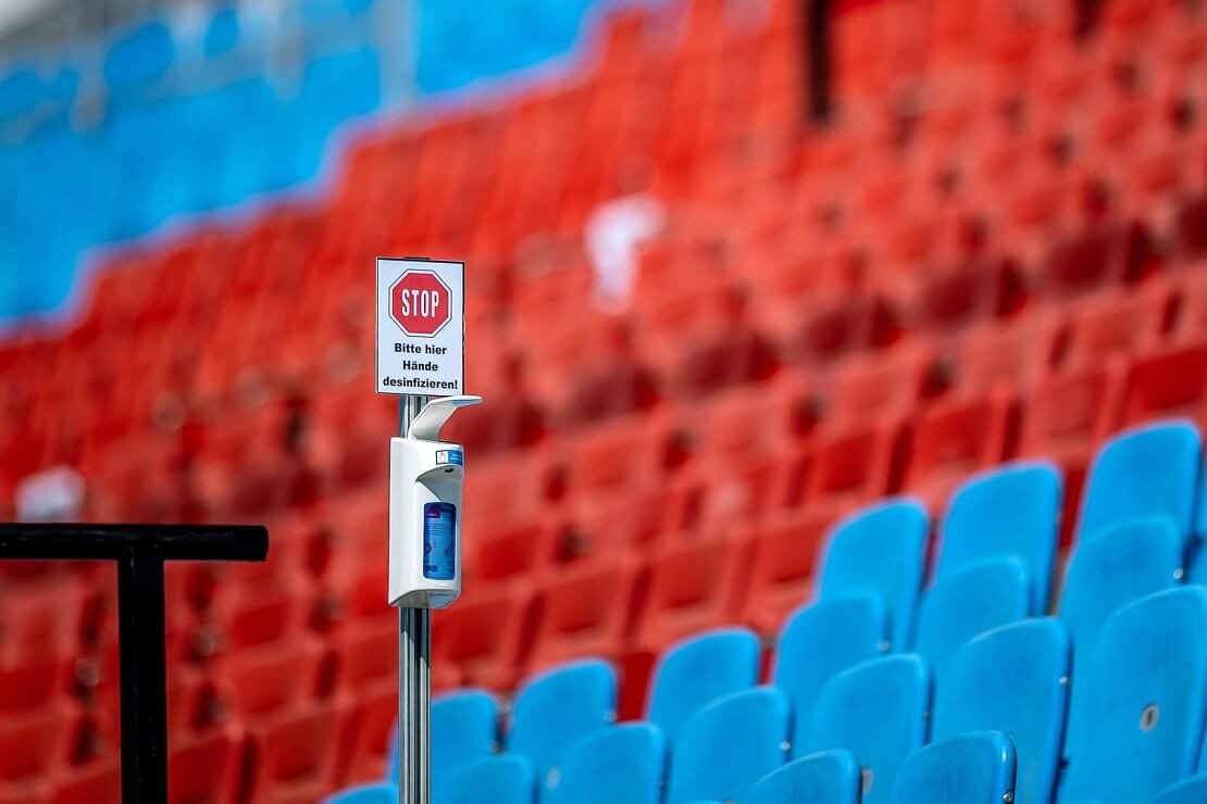 Leere Tribüne mit Handdesinfektionsmittel und Hinweis-Schild