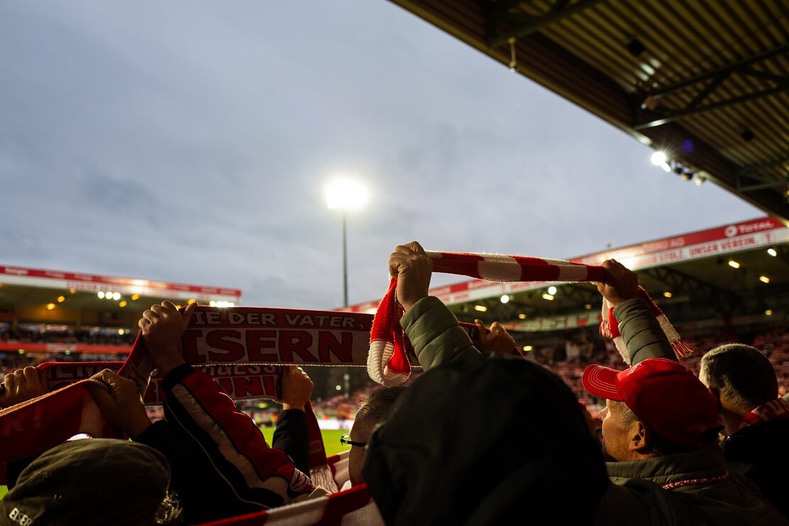 Fans stehen im Stadion und halten fanschals der Union Berlin hoch