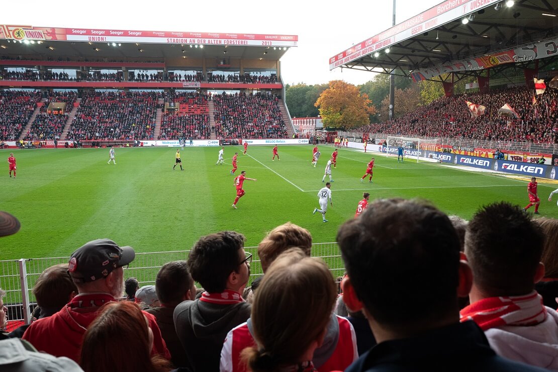 Union Berlin spielt in einem Stadion im Vordergrund sitzen Fans