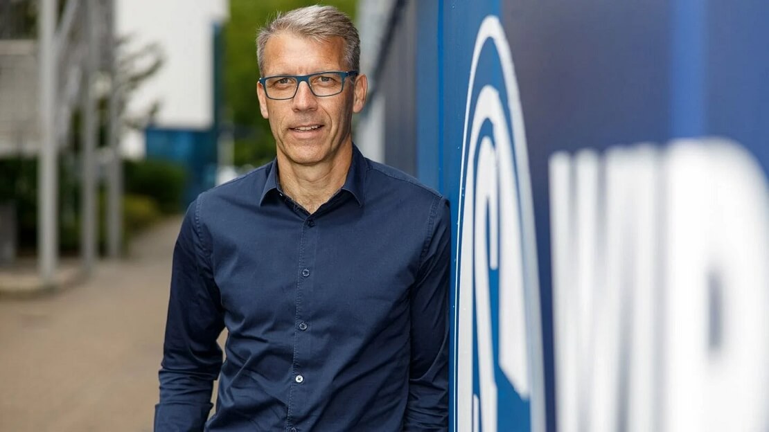 Peter Knäbel neben dem Wappen von Schalke 04