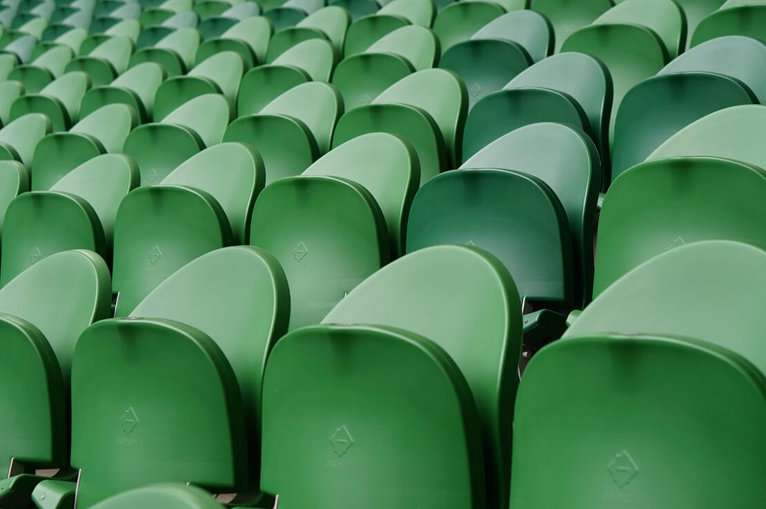 Leere, hochgeklappte grüne Sitze in einem Stadion