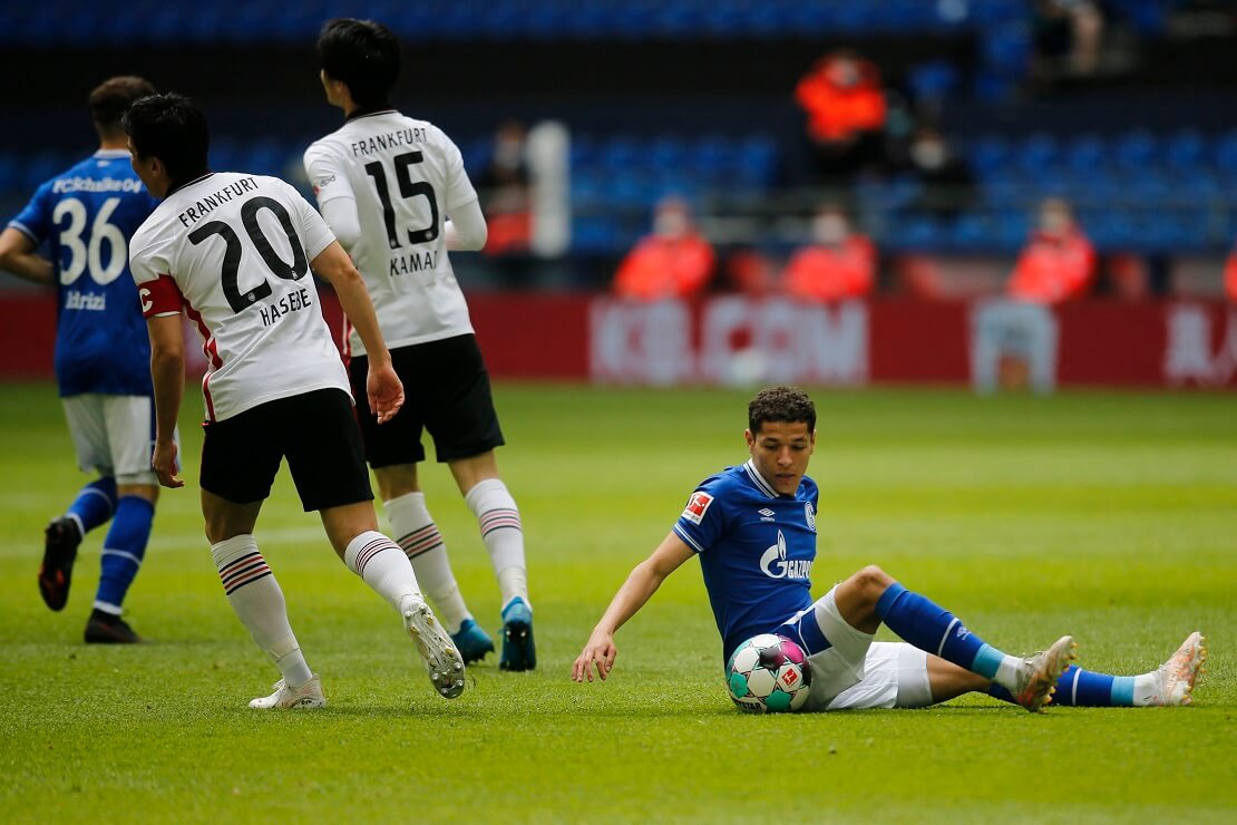 Schalkes Amine Harit sitzt neben dem Ball auf dem Boden, hinter ihm laufen Frankfurter Spieler weg