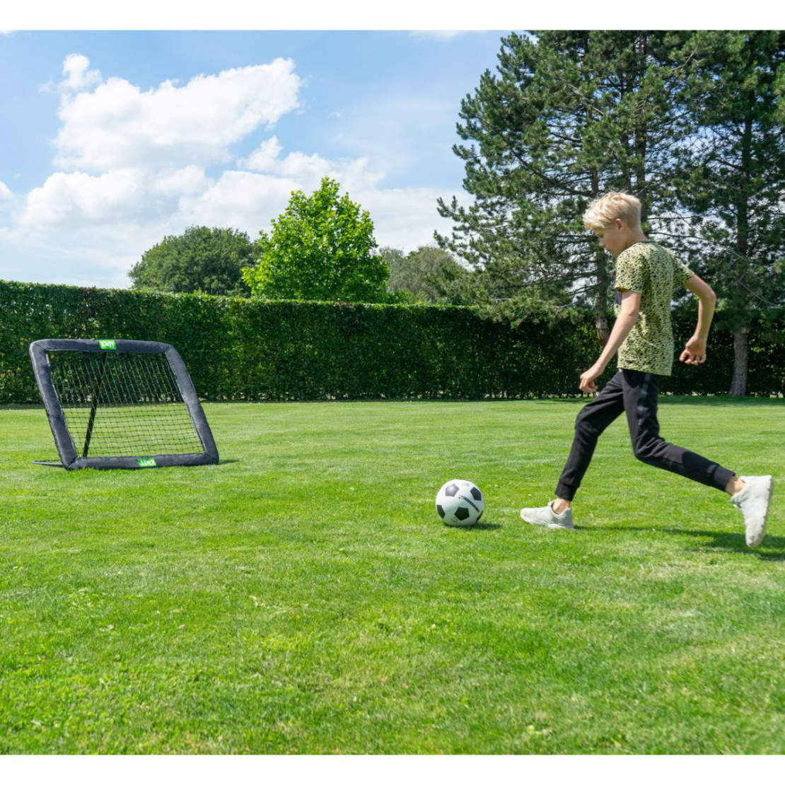 Ein Junge schießt einen Fußball auf einen Fußball Rebounder