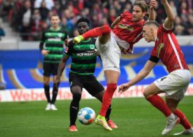 Lucas Höler vom SC Freiburg spielt den Ball mit einem artistischen Sprung, im Hintergrund Spieler von Greuther Fürth