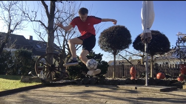 Ein junger Mann macht im Garten Tricks mit einem Fußball