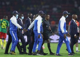 Schiedsrichter wird auf das Spielfeld in Kamerun, Komoren eskortiert