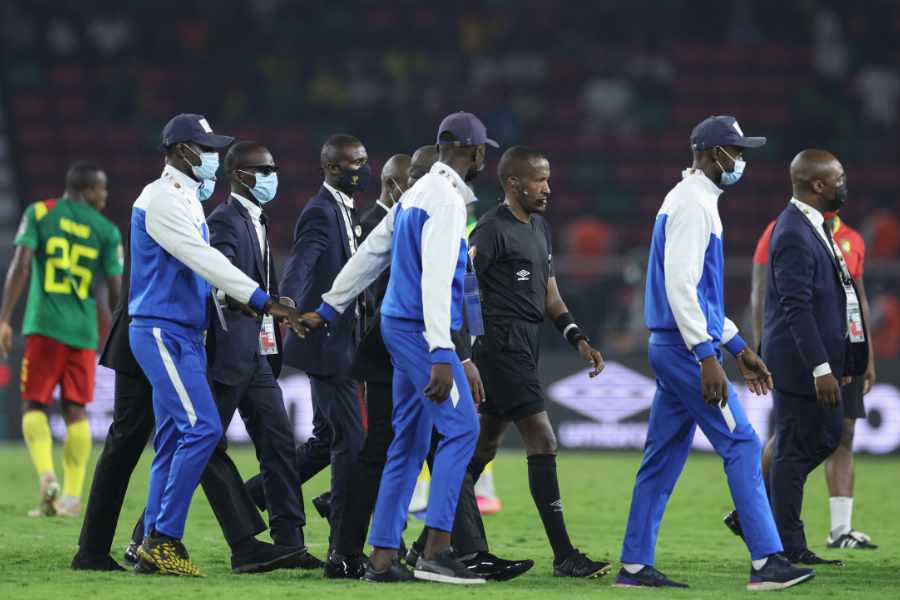 Schiedsrichter wird auf das Spielfeld in Kamerun, Komoren eskortiert
