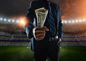 Nahaufnahme von Mann mit Geld in der Hand im Hintergrund ein Stadion