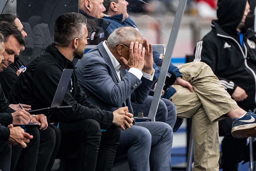 Felix Magath sitzt mit Händen im Gesicht neben anderen Menschen