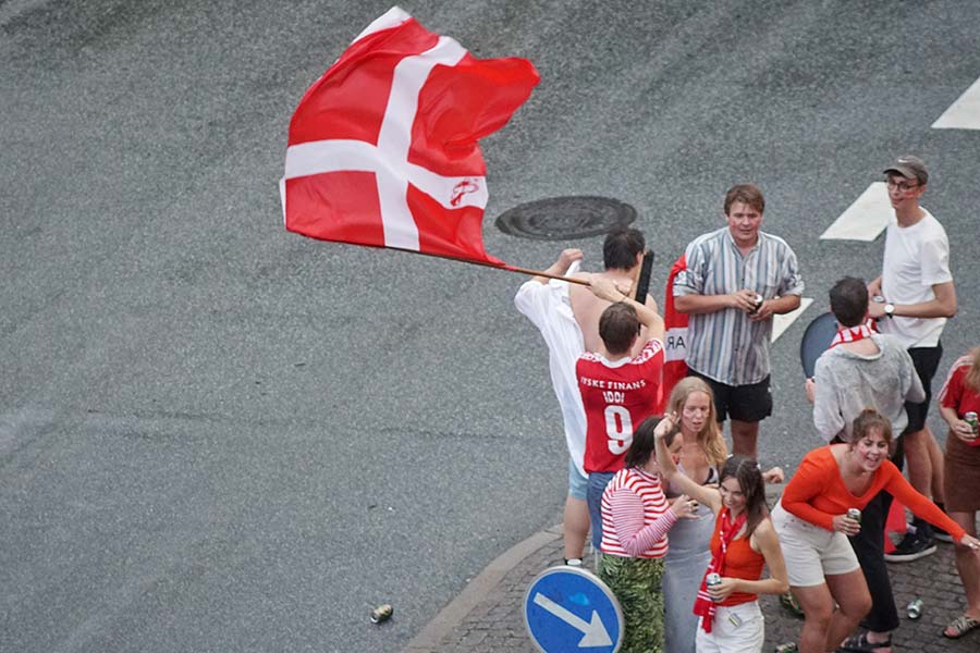 Dänemarkfans jubeln mit einer Flagge auf der Straße