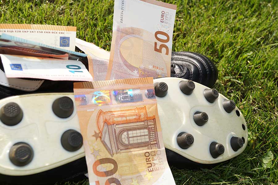Fußballschuhe auf dem Rassen mit 50 Euro Scheinen auf den Schuhen